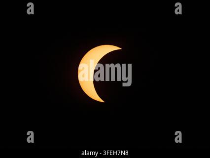 Crescent sun during a partial solar eclipse against a black sky Stock Photo