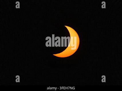 Orange crescent sun during a partial solar eclipse Stock Photo