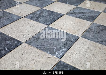 Gray marble and off-white travertine stone tiles with checkboard pattern. Flooring. Full frame, background and texture.. Stock Photo
