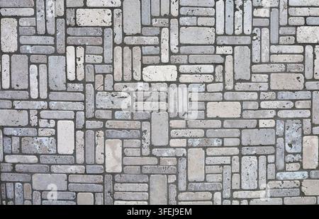 Old tiled floor made of stone tiles arranged geometrically on black concrete. Colors are grau and off white. Full frame, background and texture. Stock Photo