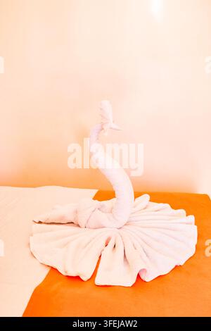 swan folded out of towels on hotel bed Stock Photo