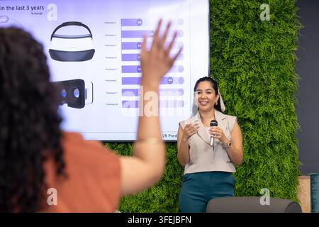 Diverse female coworkers presenting VR headset data in meeting room with microphone, copy space Stock Photo