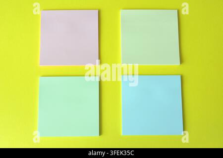 Four Square Sticky Notes on Yellow Background, high angle view, copy space Stock Photo