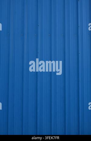 Blue corrugated textured metal surface with vertical ridges, light scuff marks, blue-coated fasteners Stock Photo