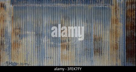 Blue tinted corrugated galvanized metal surface with rust showing a blue upper band, distressed rusted side panels Stock Photo
