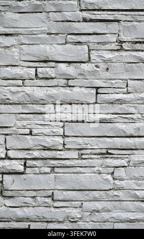 White painted machine-cut sawn stone masonry surface showing irregular rectangular cut stone blocks, black mold growth, and rough stone faces Stock Photo