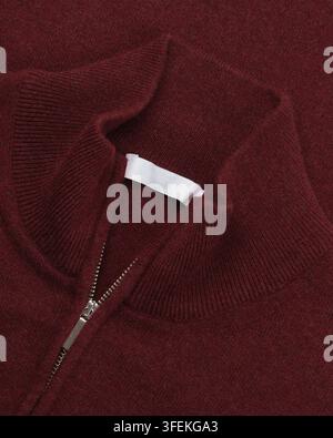 Close-up of a burgundy knitted sweater featuring a mock neck collar and metal half zipper. Detailed studio product photograph. Stock Photo