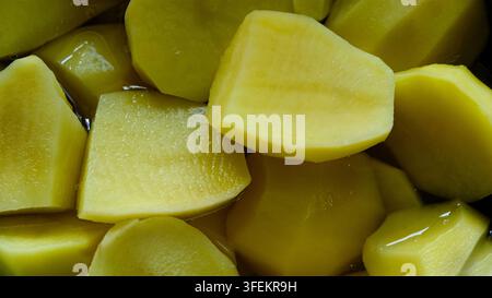 Freshly peeled and chopped raw potato chunks soaking in water, preparing for cooking or boiling, showcasing a culinary food preparation concept. Stock Photo