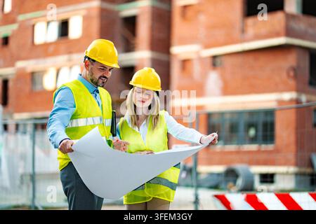 Engineers reviewing blueprint at construction site Stock Photo