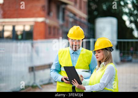 Architects using digital tablet at construction site Stock Photo
