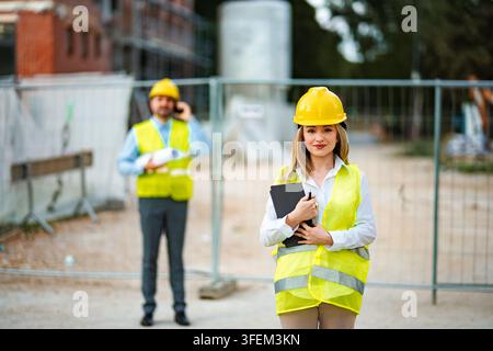 Female engineer holding tablet with male colleague on construction site Stock Photo
