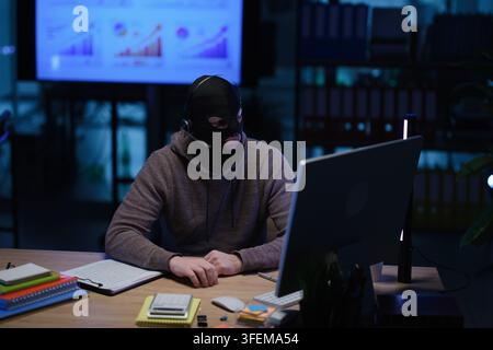 Fraud in mask and headset hacks access to personal accounts Stock Photo
