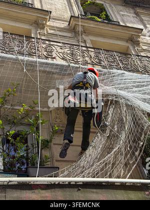 Paris, France, Construction WOrker Working on Facade of Parisian Building, Installing Protective Netting Stock Photo