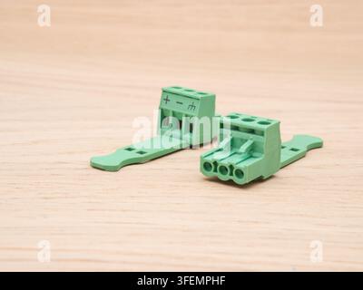 Green Electrical Terminal Blocks on Wood - Two green plastic electrical terminal blocks with screw connectors are neatly arranged on a light wooden ba Stock Photo