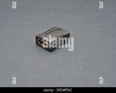 Black HDMI Adapter Connector - A close-up studio shot of a black HDMI adapter or connector with gold-plated contacts on a neutral gray background, hig Stock Photo