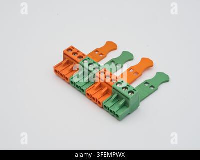 Electronic Terminal Blocks on White Back - A close-up shot of multiple orange and green electrical terminal blocks, used for connecting wires, arrange Stock Photo