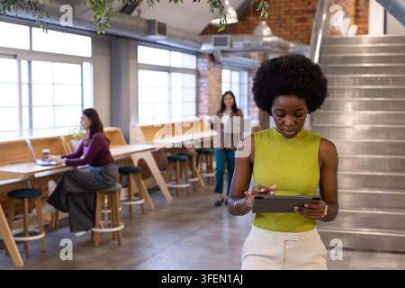 Diverse female coworkers in casual working at coworking space using tablet, laptops and coffee Stock Photo
