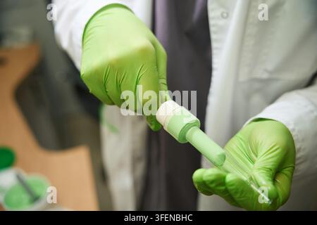 Adult scientist in lab coat conducting experiments with pipette Stock Photo