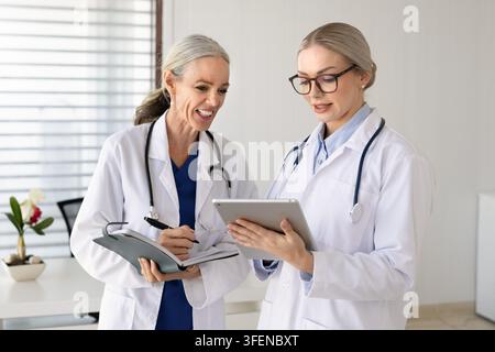 Two female doctors discussing patient information on digital tablet Stock Photo