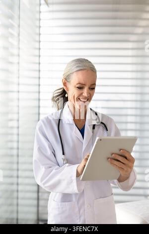 Smiling woman doctor checking digital tablet in clinic Stock Photo