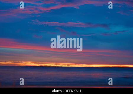 Vibrant Tropical Ocean Sunset with Dramatic Purple Clouds and Colorful Evening Sky Stock Photo
