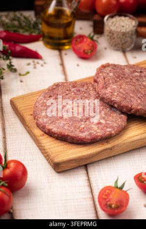 Raw burger patties on wooden cutting board Stock Photo