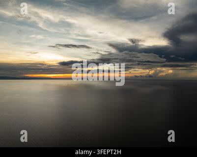 Sunset light with orange glow and clouds reflecting on calm sea horizon. Camotes, Philippines. Stock Photo