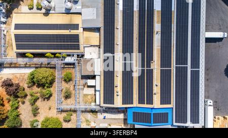 Aerial view of an industrial facility featuring extensive solar panel arrays on the roof, metal piping, and surrounding greenery in Sabac, Vojvodina, Stock Photo