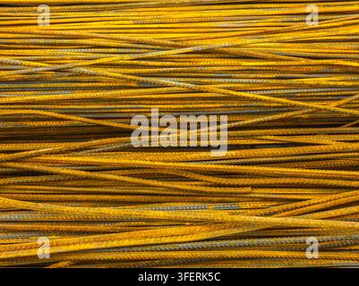 Abstract view of a densely packed pile of rusty rebar. The metal rods exhibit a rich orange-brown patina, highlighting their textured surface and imperfections. Stock Photo