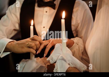 Groom placing a wedding ring on a bride finger during a traditional candlelit ceremony, capturing intimacy and lifelong commitment Stock Photo