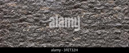 Dark gray marble tiles creating a rough textured stacked stone wall pattern Stock Photo