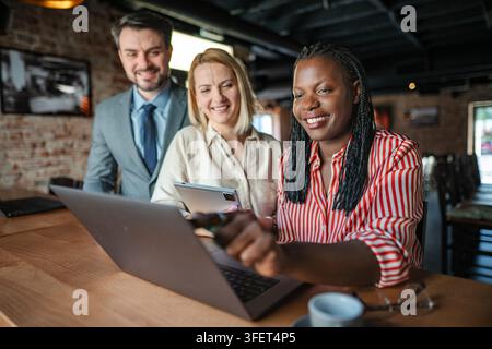 Business team collaborating on laptop and tablet at cafe Stock Photo
