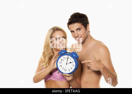 Time change and clock change from summer time to winter time, couple changes the time on the alarm clock, alarm clock shows 2.00 AM, studio recording Stock Photo