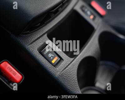 Close-up of car heated seat control switch. High setting activated on the panel. Black textured dashboard has red 'PRESS' button. Orange indicator lig Stock Photo