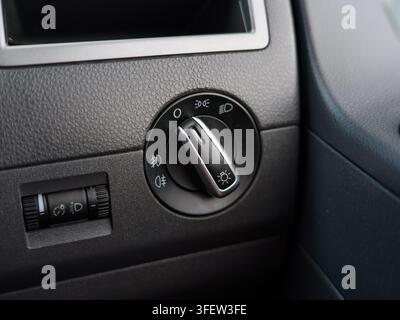Dark gray plastic dashboard detail. Circular control knob with light settings. Sun icon and car symbol visible. Close-up automotive interior shot. Ide Stock Photo
