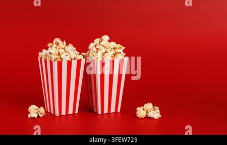 High-quality image of two full popcorn boxes with scattered kernels on a bold red surface. Represents fun, entertainment, and shared movie moments. Gr Stock Photo