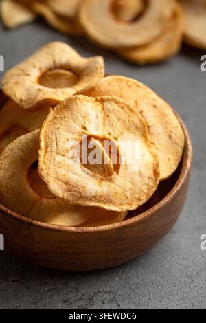 Dried apple rings in wooden bowl on grey backdrop Stock Photo