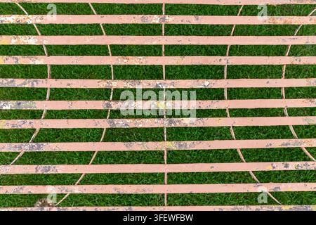 Weathered Rusty Metal Grid with Peeling Paint and Green Grass Background Stock Photo