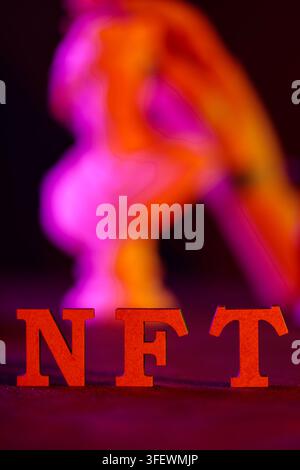 NFT text in red letters on dark background with blurred colorful neon lighting effect Stock Photo