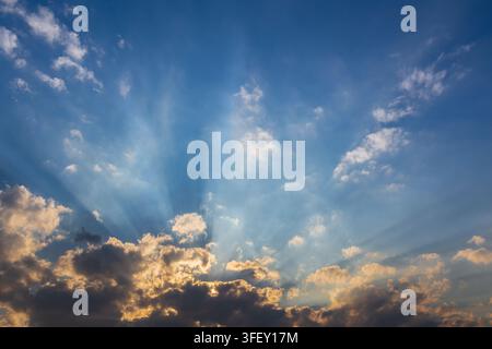 Cloudy sky during sunset with rays of sun hidden behind the clouds. Stock Photo