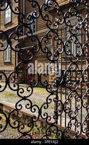 Tallinn, Estonia - 4 September 2026: Wooden house in Kadriorg seen through an ornate wrought iron gate. Stock Photo