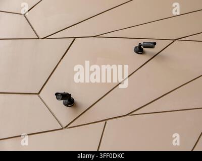 Security camera mounted on modern geometric paneled beige exterior wall at the National Museum of Qatar in Doha. Stock Photo