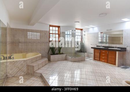 Spacious Luxury Bathroom: A bright and airy spacious bathroom featuring a large jacuzzi tub, a walk-in shower with glass enclosure, and double vanity Stock Photo