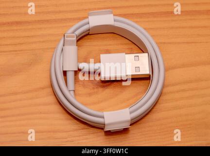 Apple USB to lightning connector cable on wooden table Stock Photo