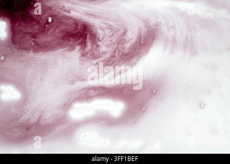 An abstract background featuring a fluid, swirling mixture of soft pink and white liquid paints, creating a beautiful marble-like textured effect Stock Photo