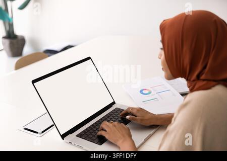 Businesswoman typing on laptop keyboard with white mockup screen Stock Photo