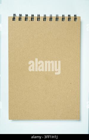 A blank brown kraft paper spiral notebook lying flat on a light background. Perfect mockup template for stationery designs, office, and school supplie Stock Photo