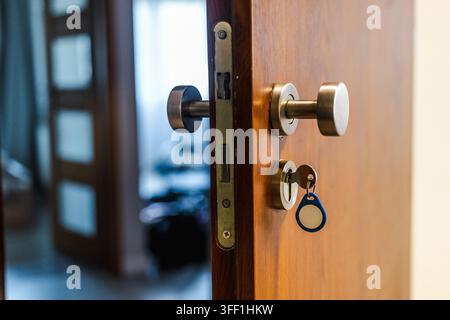 Close-Up of Key Inserted in Lock on Open Wooden Door Stock Photo