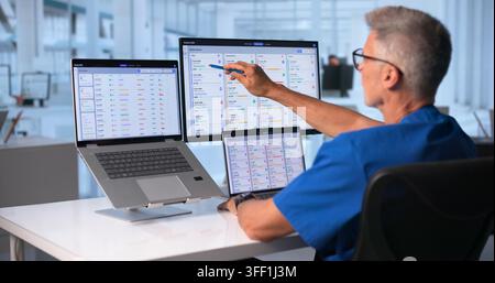 Doctor Uses Touchscreen Computer To Review Patient Data Carefully. Stock Photo