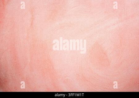 A soft pink and coral textured plaster background with a subtle, fine-grained stucco finish Stock Photo